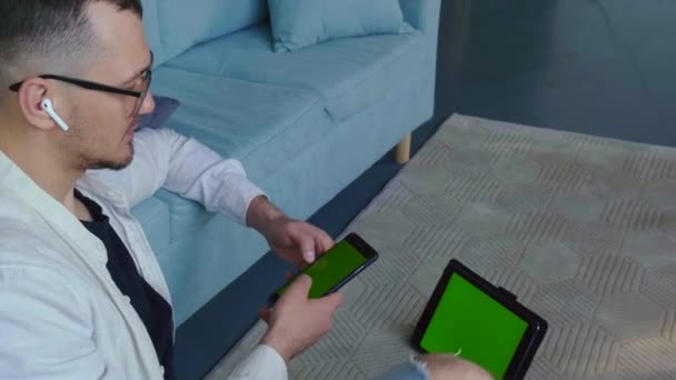 Відео з чоловіком, який сидить на підлозі і використовує сучасні технології, щоб мати можливість працювати з дому під час пандемії — стокове відео