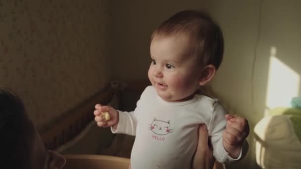 Video with a mother playing with her baby holding it up in the air. Baby smiling at his mother and then looking at the camera in amazement — Stock Video