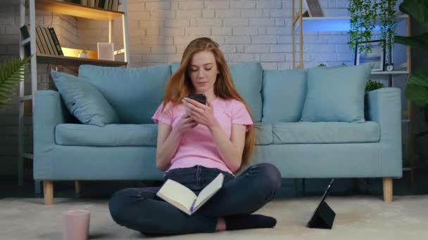 ビデオだ。長い赤い髪の女性は、オンラインレッスンから休憩を取り、友人にメッセージを書いています。遠隔学習 — ストック動画