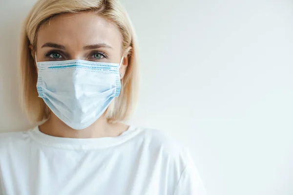 Portretul unei femei blonde pe un fundal alb purtând o mască medicală. Protecţia virusului. Copiați spațiul — Fotografie, imagine de stoc