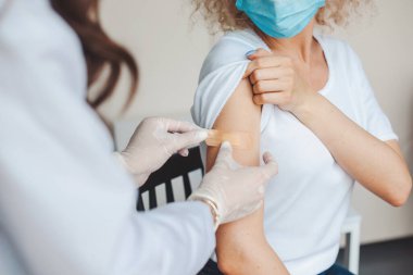 Corona virüsü aşısını verdikten sonra genç bir kadının koluna yama yapıştırıyor. Antiviral aşı.