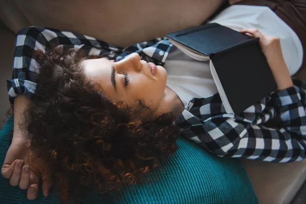 Utsikt från sidan av en kaukasisk flicka som somnade med boken på bröstet. Lockigt hår — Stockfoto