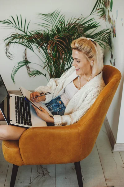 Mujer caucásica tomando cursos en línea sentado en sillón con ordenador portátil. Estudio en línea. — Foto de Stock