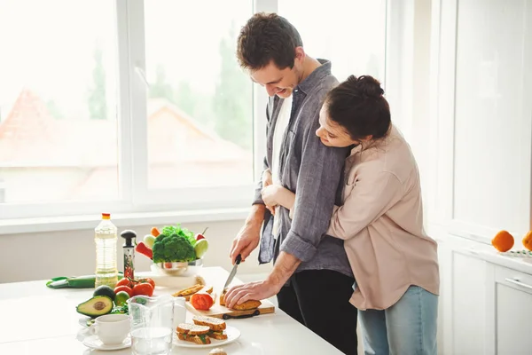 Coppia cucina cena mentre in piedi in cucina a casa. Donna che abbraccia l'uomo. Godere del tempo insieme. — Foto Stock