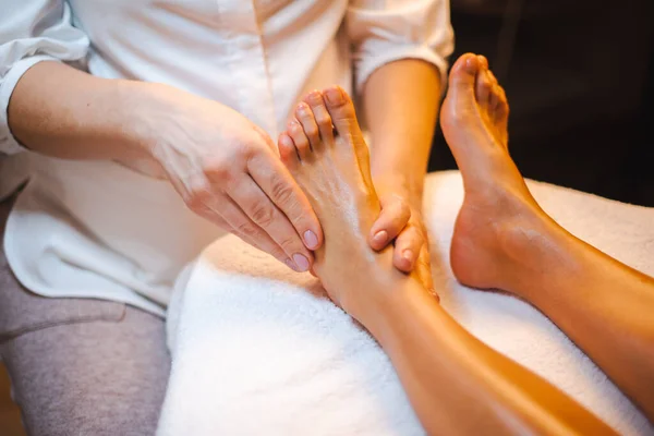 Masuje ręce robiąc masaż stóp refleksologii do klienta w centrum spa. Relaksujący masaż. Pielęgnacja ciała w spa. Zabieg kosmetyczny. — Zdjęcie stockowe