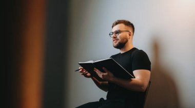 Sandalyeye oturmuş elinde defterle birileriyle konuşan bir adamın yan görüntüsü. Gülümseyen adam. İzole edilmiş.