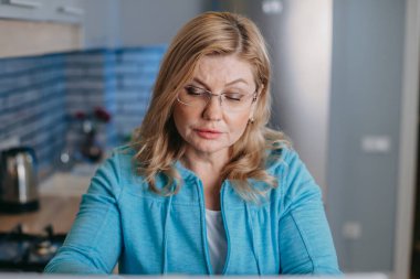 Kafkasyalı orta yaşlı bir iş kadınının portresi dizüstü bilgisayar kullanıyor, masada oturuyor. Uzaktan kumanda. 40 'lar
