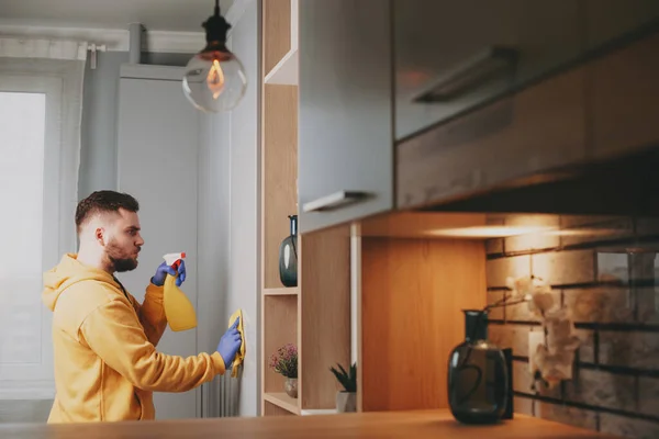 Kaukasier putzt Küche mit Spray und Staubtuch. Seitenansicht — Stockfoto