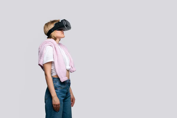 Visão lateral da jovem usando óculos de vídeo virtuais retorna ao espaço de texto. Experiência VR. Espaço para cópia. Isolado no fundo branco. Estilo de vida moderno mulher — Fotografia de Stock