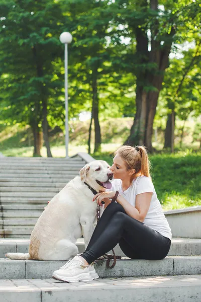 개를 데리고 공원 계단에 앉아 있는 여자. 애완 동물 과 주인 사이의 우정 — 스톡 사진