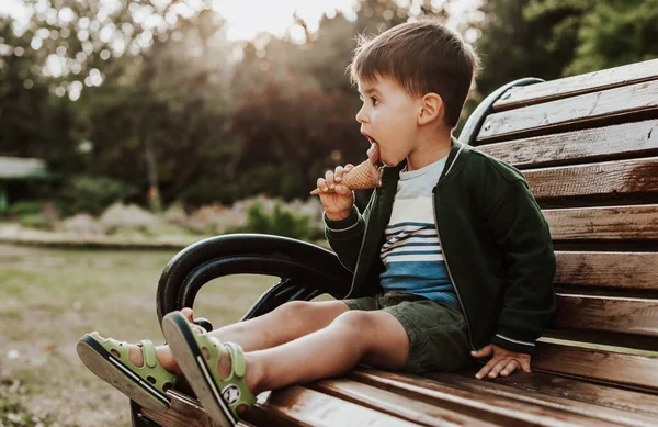 Parktaki sandalyede dondurma yiyen bir çocuğun yan görüntüsü. Böylece Uluslararası Çocuk Günü 'nü kutluyoruz.