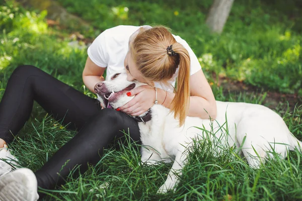 Szőke nő a kutya-retrieverével a parkban. Kaukázusi lány játszik kutyával a füvön. Szabadtéri nyári szórakozás. Kutyatanítás. Arany retriever. — Stock Fotó
