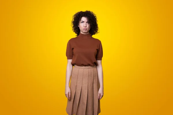 Retrato de mulher ofendida descontente com cabelo encaracolado olhando com raiva para a câmera isolada sobre o fundo do estúdio amarelo. — Fotografia de Stock