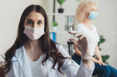 Doktor, hastalar için sıvı aşılarla dolu bir şırınga tutuyor. Konsept: hastalıklar, tıbbi bakım, bilim. Virüs koruması. Doktor eli..