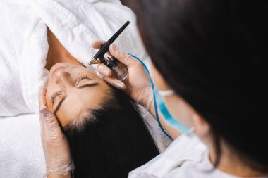 Kozmetik uzmanlarının elleri, bir kaplıca salonundaki müşteriler için su soyma prosedürü yapar. Yüz temizleme konsepti. Dermatoloji, kozmetoloji. Sağlık hizmetleri.