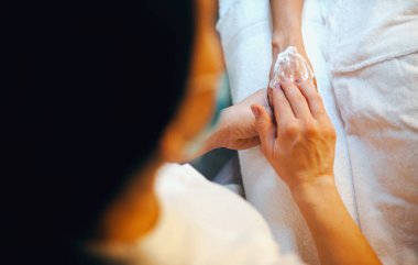 Masözlerin elleri müşterinin ellerine krem sürüyor. Kozmetik güzellik prosedürü. Güzel cilt. Vücut bakımı.