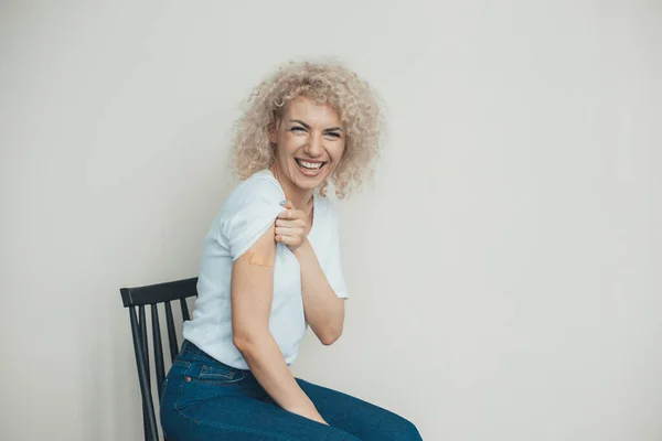 Aşılanmış koluna bandaj yapıştırılmış mutlu beyaz kadın. Kıvırcık saçlı. Yetişkin aşısı, çovid aşısı. Corona virüsü aşılama. Virüs koruması. — Stok fotoğraf