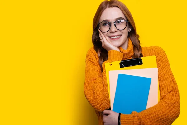 Aufgeregte kaukasische Studentin mit Brille und Büchern auf gelbem Hintergrund. Freiraum. Leere Räume. — Stockfoto