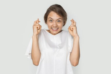 Heyecanlı genç bir kadının portresi kameraya bakıp şans diliyor beyaz arka planda izole edilmiş bir şekilde. Vücut dili kavramı