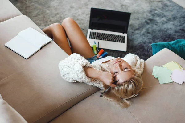 Vista superior de una mujer que usa un portátil sentado en el suelo e inclina la cabeza desde el sofá sintiéndose cansada en el suelo. Educación en línea. Educación en el hogar durante el encierro. — Foto de Stock