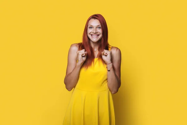 Zevkli kızıl saçlı kadın sarı arka planda izole bir şekilde yumruğunu havaya kaldırıyor.. — Stok fotoğraf