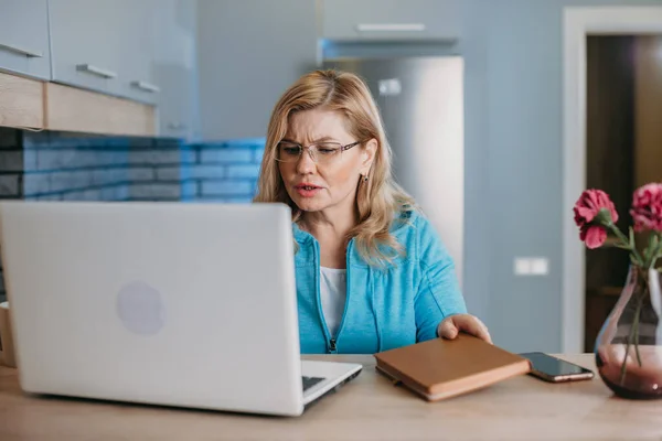 Masasında oturmuş laptoptan bilgi okuyan orta yaşlı bir iş kadınının ön görüntüsü. Ciddi bir ifade. İnternet teknolojisi. — Stok fotoğraf