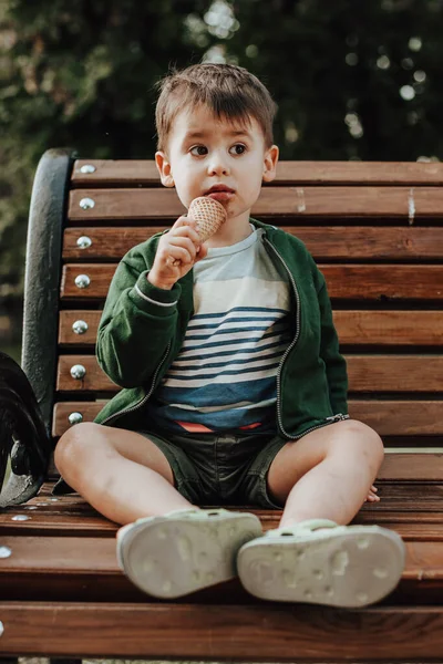 Parktaki bankta elinde dondurma tutan beyaz bir çocuk boyunda bir adam. Dondurma yiyorum. Beyaz çocuk.. — Stok fotoğraf