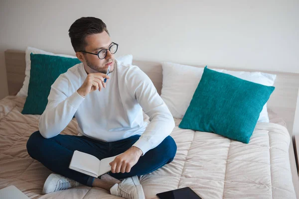 College student studying from home in his room sitting on bed. Quarantine lifestyle. — 图库照片