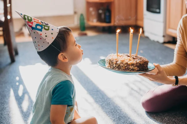 Widok na chłopca zdmuchującego świeczki na torcie urodzinowym. Świetny projekt do dowolnych celów. Święta, urodziny. Słodkie jedzenie. — Zdjęcie stockowe