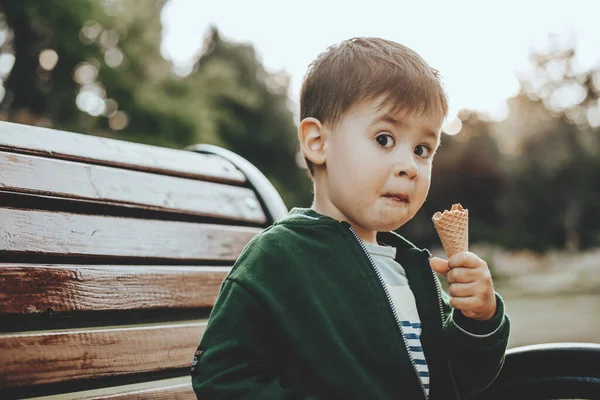 Kafkas çocuk dondurma yiyor ve parkta bankta otururken kameraya şaşkın şaşkın bakıyor. 2020 ÇOCUK — Stok fotoğraf