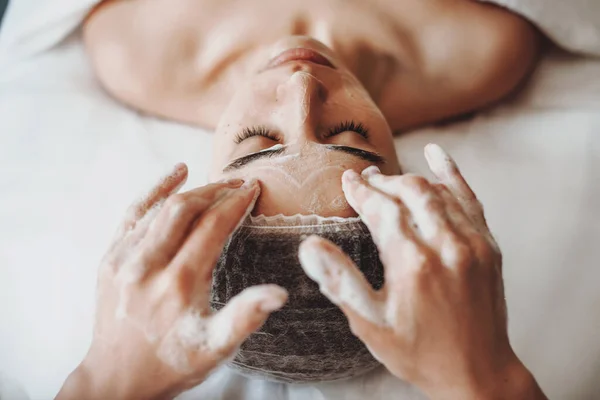 Vista superior. Mulher de limpeza rosto com espuma, uma mulher caucasiana no salão de spa. Trabalho de cosmetologista. — Fotografia de Stock