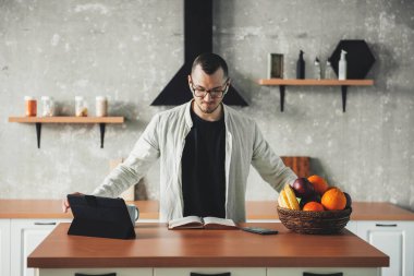 Mutfakta çalışan bir iş adamının ön görüntüsü. Covid salgını sırasında tabletler ve defterlerle akıllı çalışma.