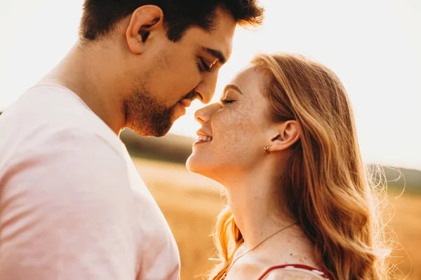 Close-up portrait of a couple having fun outdoors, kissing and hugging. Sunny summer day. Wheat field. — Fotografia de Stock