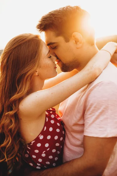 Side view of a caucasian couple standing in the middle of the wheat field hugging and kissing. Beautiful young girl. Valentines day. Wheat field. Sunny summer — стокове фото