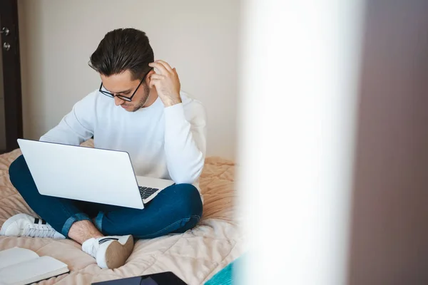 Empresario que trabaja y utiliza el ordenador portátil mientras está sentado con las piernas cruzadas en la cama. Tecnología de Internet. Comunicación en línea. —  Fotos de Stock