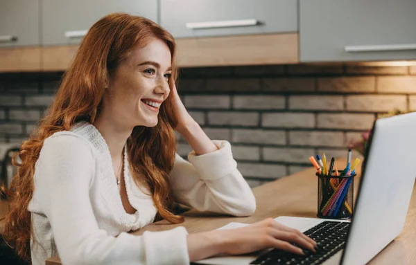 Ev ofisinde çalışan dizüstü bilgisayarı olan kızıl saçlı bir kadının yan görüntüsü. İnternet teknolojisi. Çevrimiçi iletişim. İş teknolojisi. — Stok fotoğraf
