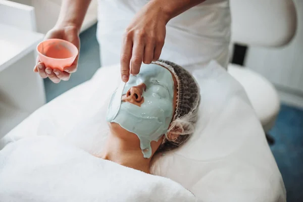 Cosmetologist applying a alginic mask to the face of a young woman in beauty salon. Beauty skin female face. Young woman skin care. Medical treatment. Facial — 图库照片