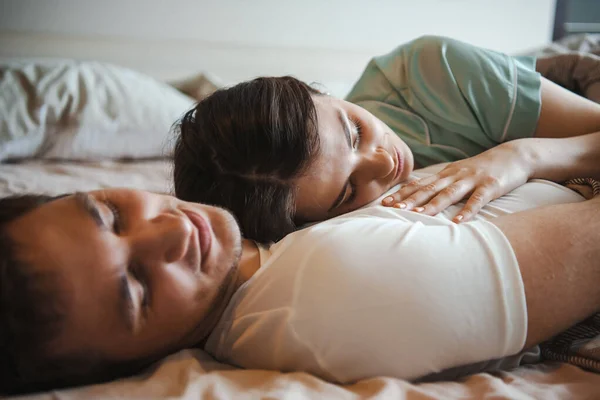 Couple caucasien couchant ensemble sur leur lit à la maison. Matin de famille. — Photo