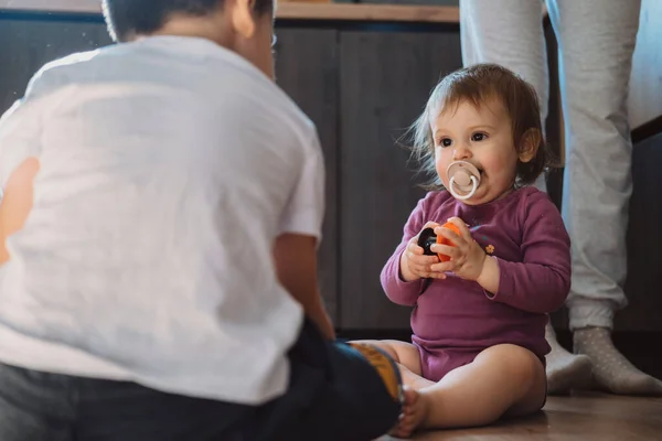 Fratello e sorellina che giocano con i giocattoli sul pavimento di casa. I bambini giocano. Tempo di famiglia. — Foto Stock