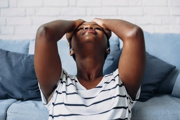Retrato de cerca de una mujer afroamericana agotada agarrándose la cabeza sintiendo estrés, sufriendo de dolores de cabeza. — Foto de Stock