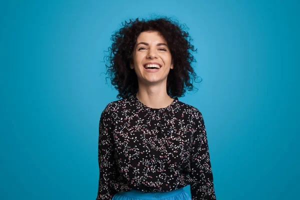 Portrait d'une femme caucasienne aux cheveux bouclés souriant isolé sur fond bleu. Portrait rapproché. Une personne positive. Modèle de mode beauté. — Photo