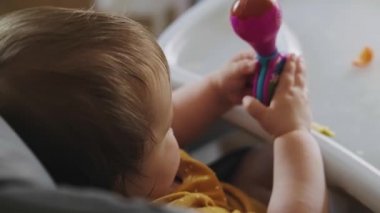 Baby girl sitting in baby chair and playing with toy. Healthy lifestyle. Baby care. Beautiful girl.