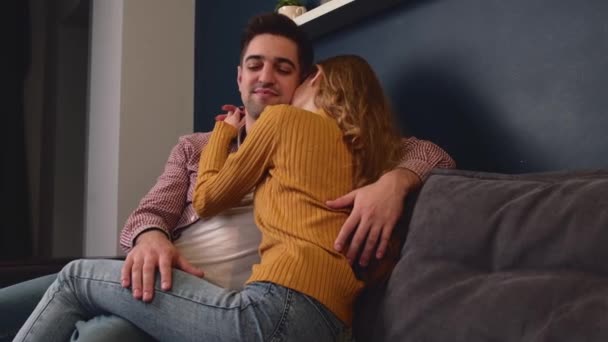 Kaukaski mężczyzna przytula swoją dziewczynę leżąc na kanapie i relaksując się — Wideo stockowe