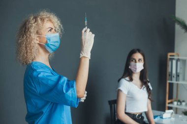 Portrait of a curly nurse who is holding syringe near the patient. Influenza pandemic medical health. Medical treatment. Medical uniform. Laboratory equipment