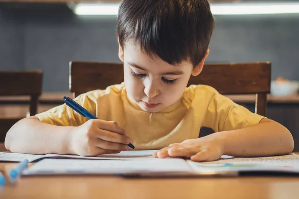 Caucasian boy studying at home writing notes sitting at desk. Front view. Distance education. Front view. Online education. —  Fotos de Stock