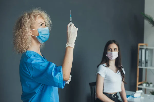 Portrait of a curly nurse who is holding syringe near the patient. Influenza pandemic medical health. Medical treatment. Medical uniform. Laboratory equipment — Stock Photo, Image