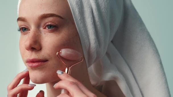 Retrato de cerca de una mujer con toalla en la cabeza usando rodillo de jade en la cara. Tratamiento de rejuvenecimiento. Tratamiento facial de la piel. Cuidado facial de la piel. — Vídeos de Stock