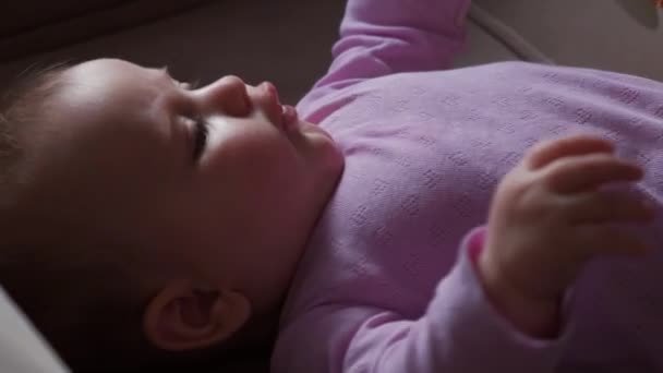 Das kleine Mädchen bewegt sich, während es auf dem Rücken in einem Kinderbett liegt. Schlafenszeit. — Stockvideo