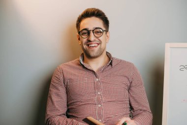 Teacher smiling and explaining homework while looking at camera