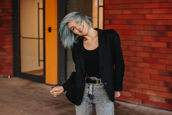 Stylish businesswoman walking in urban city business street smiling and looking at camera. Blue hair. — Stockfoto